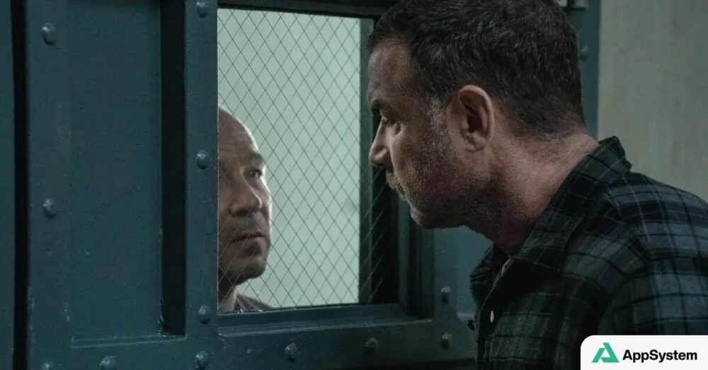Liev Schreiber face à une vitre grillagée dans une cellule