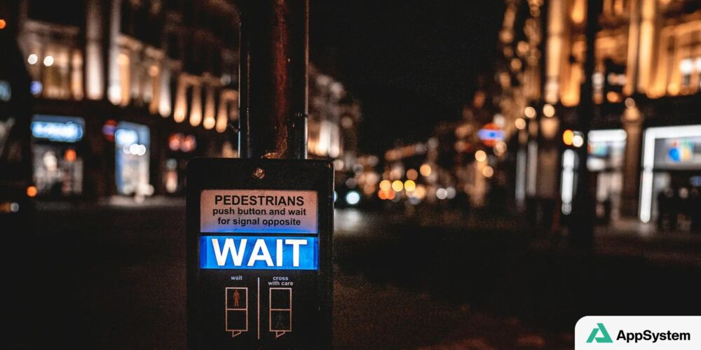 Signal piétonnier affichant « WAIT » dans une rue nocturne