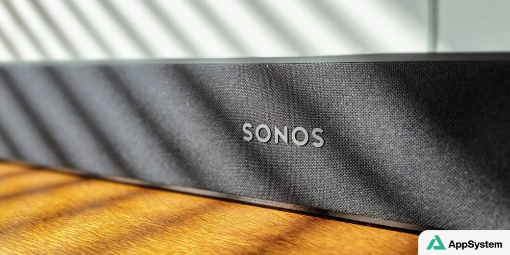 Enceinte connectée Sonos noire posée sur une table en bois