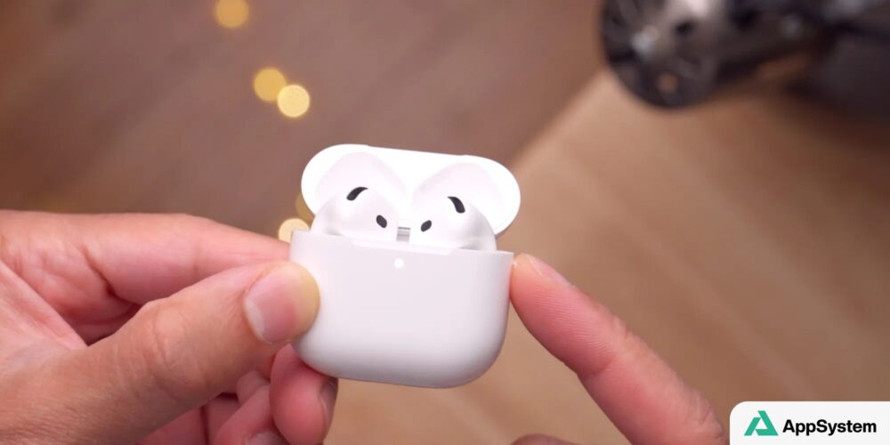 Boîtier ouvert contenant deux écouteurs AirPods blancs, tenu en main