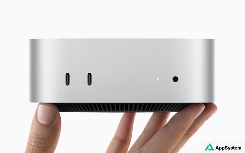 Mac mini argenté tenu entre les mains, avec ports visibles