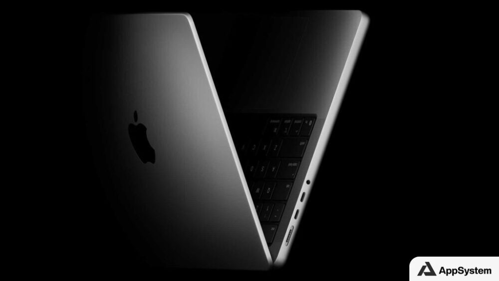 MacBook ouvert photographié en clair-obscur, vu de dos