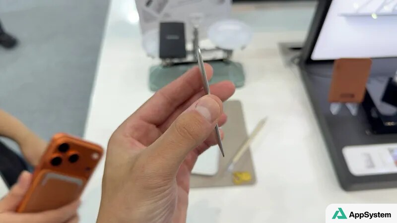Accessoire métallique fin présenté au-dessus d’un présentoir d’accessoires Apple