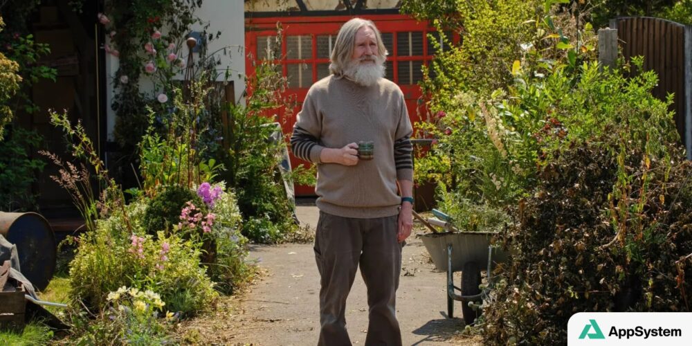 Homme barbu debout dans un jardin avec une brouette
