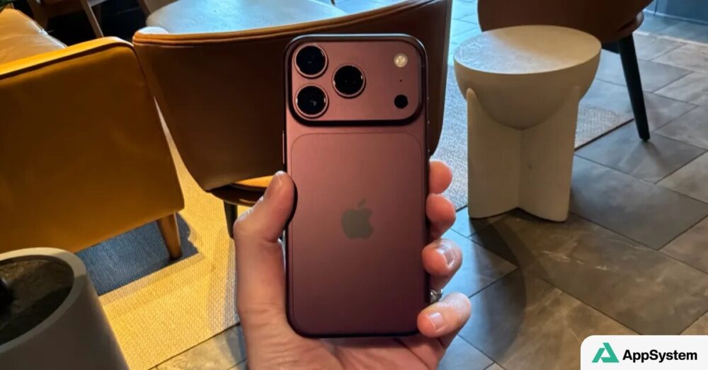 Dos d’un iPhone rose tenu à la main, montrant ses trois caméras