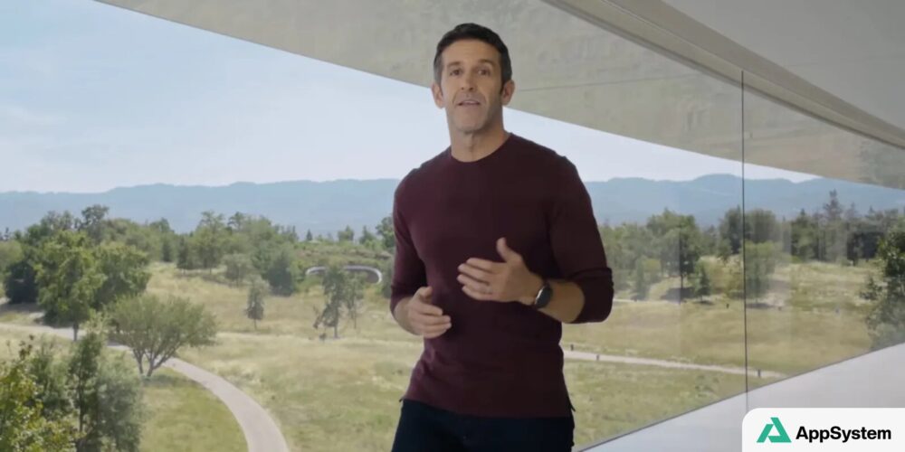 John Ternus s’exprime dans un bâtiment Apple vitré, devant un paysage arboré.